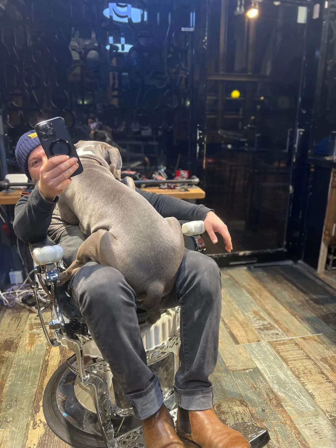 Onur in the barber's chair with a dog on his lap