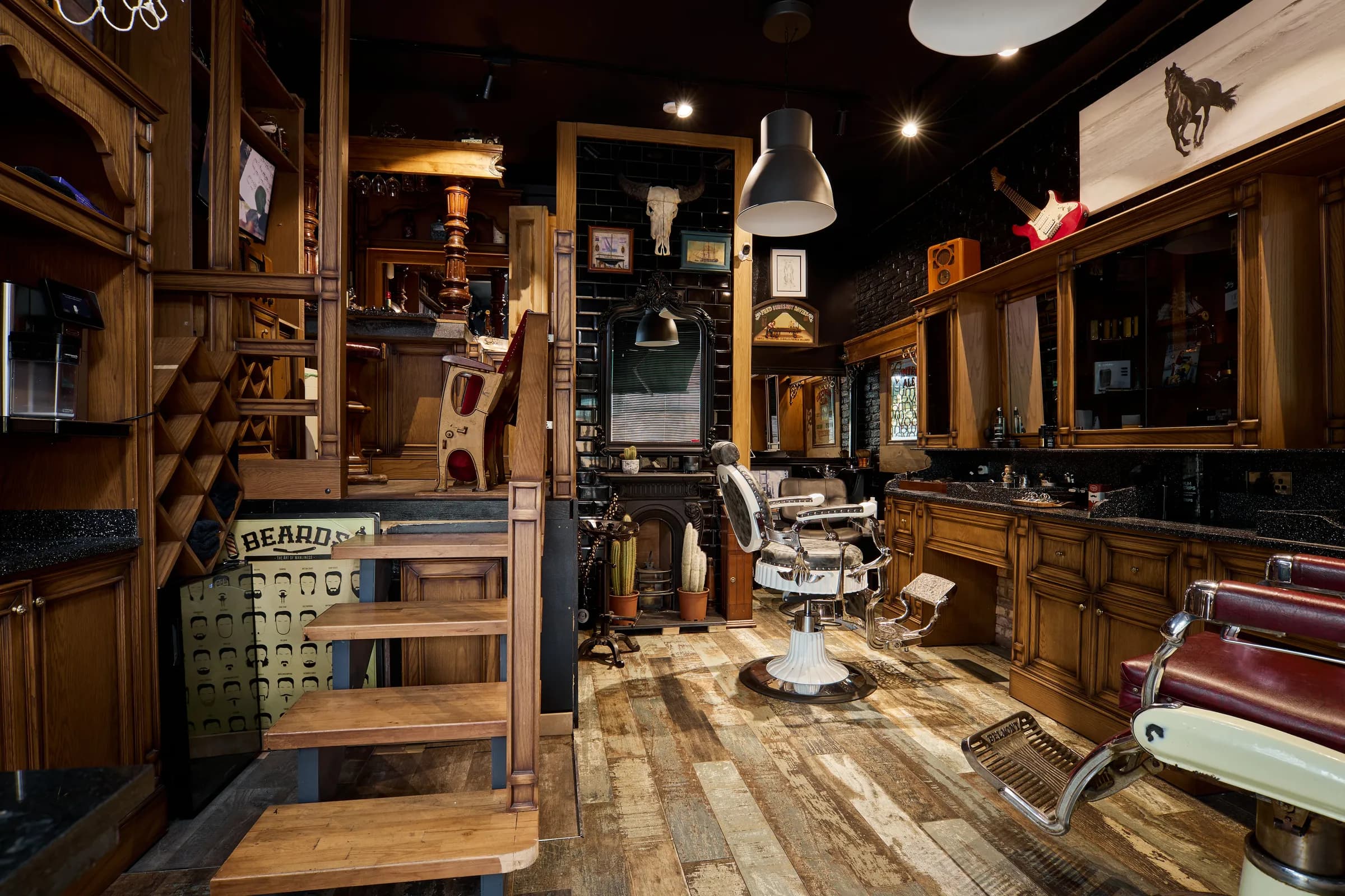 The shop from the door: a barber's chair on reclaimed boards, dark wood cabinets and low lamps